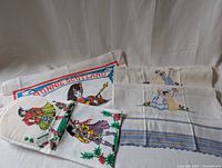 Four tea towels laid out on a white surface showing the variety and embroidered designs
