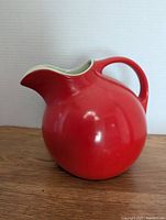 Front angle view of the vibrant red spherical pitcher with handle and spout showing its shape and color.