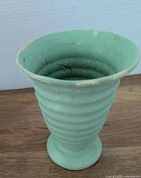 Front view of vintage Medalta vase showing ribbed pattern, flared mouth, and chalky textured green glaze with some wear and rubbing.