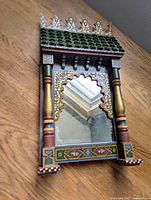 Full view of the Moroccan wall/desk mirror showing the green tiled roof top, detailed painted motifs, and wooden side pillars.