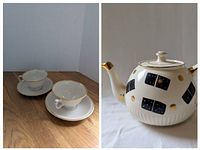 Image showing two white porcelain cups and matching saucers with gold trim, placed on wooden surface.