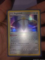Close-up photo of Aegislash Pokémon card showing holographic art and all text details.