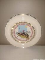 Photo of a vintage 4.5 inch Alberta Canada collectible ashtray plate. Shows the plate's front with colorful western rider artwork, skyline, and textured gold scalloped ring on white ceramic.