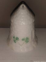 White ceramic collectible of a tower with shamrock decoration and textured details photographed against a dark background.