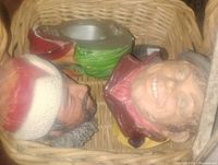 Photo showing four boson head figurines in a basket, displaying varied colors and facial features.