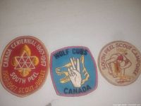 Photo showing three vintage embroidered Boy Scout patches from Canada laid out on a white surface.