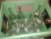 Top view showing ten clear glass bottles arranged in green crate with dividers and two bottles labeled 'Elder's Dry'.