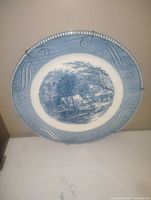 Front view of the blue and white Currier and Ives collectible plate showing the detailed rural landscape scene and patterned border