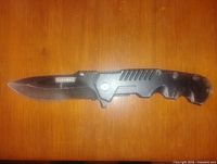 Photo showing full length of the Duramax folding knife with blade open on a wooden surface.