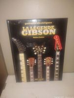 Front cover of the Gibson guitar coffee table book in French, showing five different Gibson electric guitar headstocks on black background.