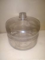 Front view of clear glass oil bottle showing cylindrical shape, threaded neck, and smooth surface.