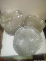 Stack of clear glass plates with ribbed textured edge and three sections separated by dividers, viewed from front and side angles.