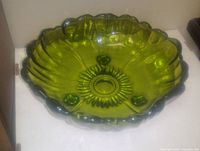 Green round glass bowl with scalloped edges, textured interior pattern, and raised circular details on the bottom surface.