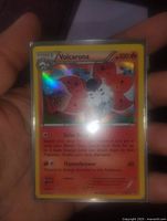 Close-up photo of Volcarona holographic foil Pokémon card held in hand, showing card details and holo shine.
