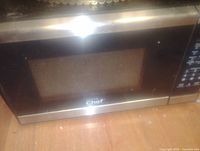 Photo of Hamilton Beach Chef microwave oven, black with control panel and door window, placed on wooden surface