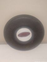 Photo of a vintage Peterbilt truck horn showing a round black textured outer rim and white central area with maroon oval badge embossed 'Peterbilt'.