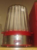 Popcorn maker with clear vertical panels and red base, showing the Cuisinart logo on a metal plate on the front.