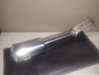 Vintage heavy metal microphone placed on black fabric against a plain wall background.