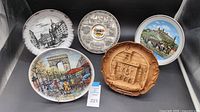 Five decorative wall plates from France, Italy, and Germany shown together on a dark background for display.