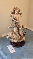 Front view showing female figure and cherubs on wood base