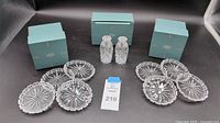 Two sets of four Lenox Mystic Crystal coasters with starburst pattern, scalloped edges, and intricate cut designs. A pair of Lenox Mystic Crystal salt and pepper shakers are positioned behind them, all displayed with original light blue Lenox packaging boxes.