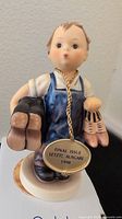 Front view of the Hummel figurine showing the child holding two pairs of shoes, and a hanging medallion with the text 'FINAL ISSUE LETZTE AUSGABE 1998'
