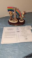 Four-piece M.I. Hummel figurine set on wooden base with rainbow and Certificate of Authenticity visible in front.