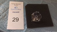 Top view of the Swarovski crystal Amur flower figurine on black foam with auction tag number 29