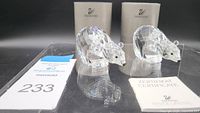 Two Swarovski crystal bear figurines side by side with certificates and original boxes behind on reflective surface