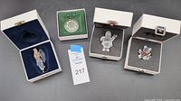 Photo showing all four Swarovski crystal ornaments and figurines in original white boxes on black background.
