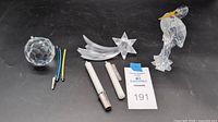 Crystal figurines and accessories including faceted sphere, shooting star, heron bird, candle holders, and clips placed on dark background with lot number card visible.