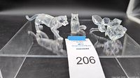 Three Swarovski crystal figurines: panther, sitting cat, and rose placed on a clear acrylic tray with auction lot tag