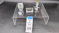 Four Swarovski crystal items arranged on a display stand: owl, heart, engraved plaque, and cockatiel.