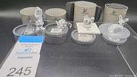 Overview of four Swarovski crystal animal figurines displayed with original packaging and certificates. Items include bear, squirrel, rabbit, and bird.