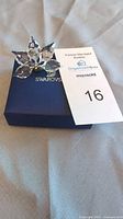 Crystal flower figurine displayed on top of the original blue Swarovski box with auction tag visible.