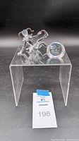 Side and front view of crystal jester figurine and round engraved crystal disc on clear acrylic stand.