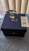Crystal whale figurine sitting on the original blue Swarovski Crystal Society box with auction tag next to it.