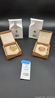 Two Swarovski floral brooches in original packaging with outer white boxes visible