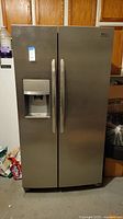 Frigidaire Gallery stainless steel side-by-side refrigerator in garage setting.