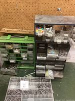 Photo showing four storage containers with numerous small drawers filled with assorted hardware items such as nails, screws, hooks, wall anchors, and washers.