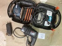 Black & Decker Mouse detail sander inside a black plastic carrying case with orange sanding pads and a small charger or battery pack next to it.