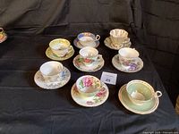 Top view showing eight assorted bone china tea cup and saucer sets in different floral and decorative patterns.