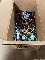 Large cardboard box filled with assorted Lego bricks and pieces of various shapes and colors.