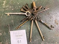 Top view showing full collection of 10 vintage skeleton keys with varied sizes and designs on a green distressed surface.