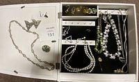 Full view of the costume jewelry lot inside the white picture frame carrying case showing multiple pieces on black velvet backing.