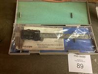 Full view of the caliper inside hard plastic case with green foam and instruction manual visible