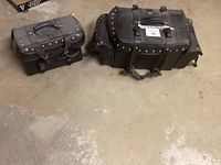 Photo showing both saddlebags on a concrete floor, highlighting size difference and metal stud detailing.