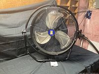 Front angled view of the large 22 inch diameter Power Fist industrial fan with three metal blades and protective wire cage.