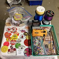 Photo showing vintage pinback buttons spread out on the Mini Maxi Shopper bag, with curling ribbon spools and other items in background.