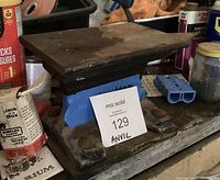 Side angle view of the single horn cast iron anvil on a workbench, showing mounting holes and surface wear.